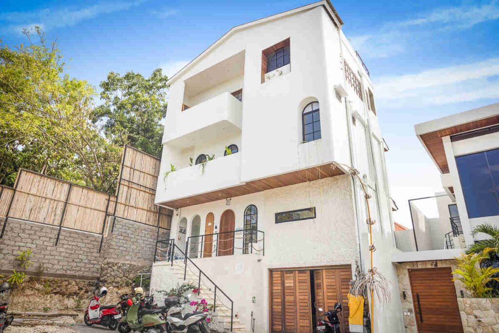 Street view of the white three-storey building at Bingin with arched timber doors and external stairs up to the Media Suite, scooters parked outside