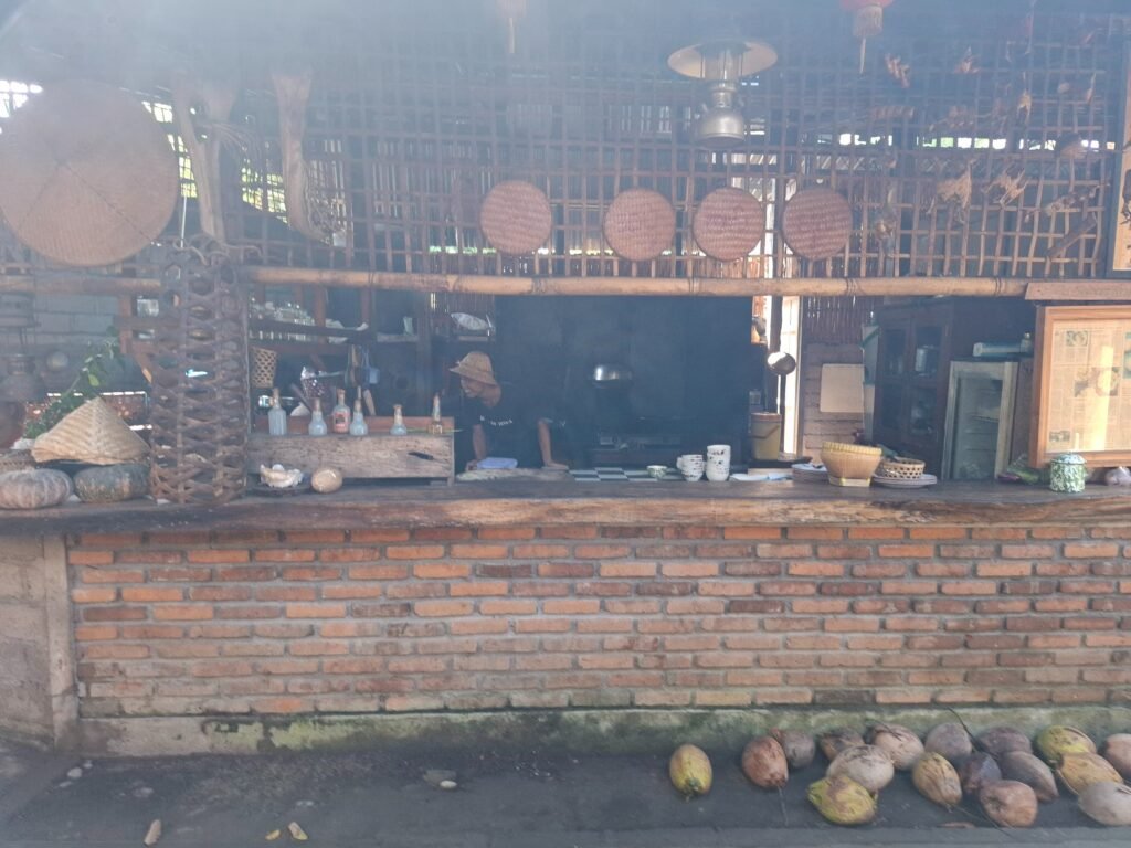 The open wood-fired kitchen at Dapur Bali Mula in Les village, north Bali, with young coconuts stacked along the brick counter