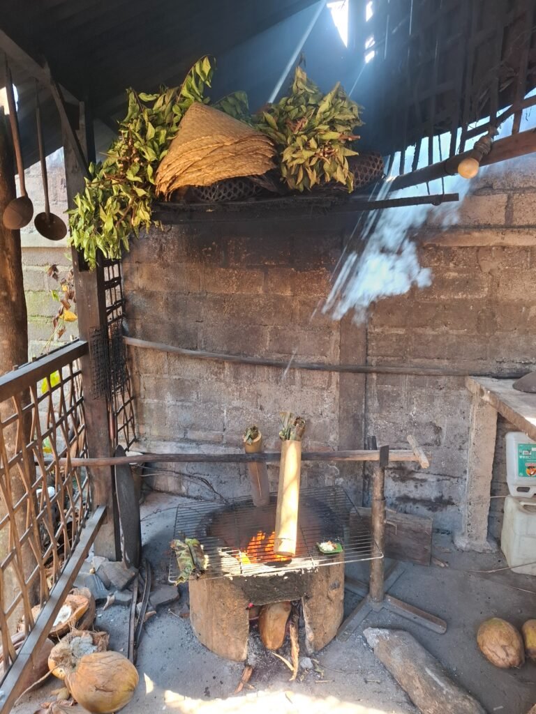 Food cooking in bamboo tubes over a wood fire at Dapur Bali Mula, with herbs drying on the rack above